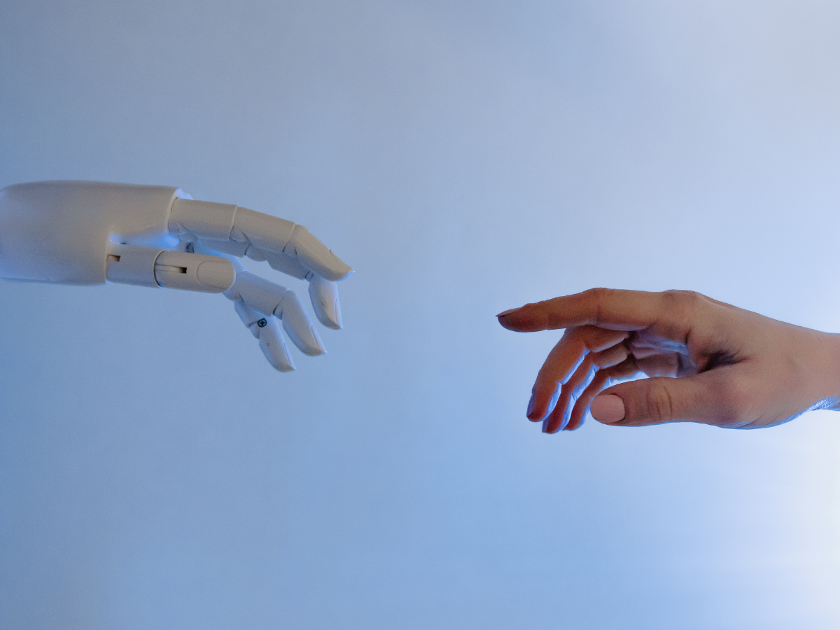 Photograph of robot hand and human hand reaching for each other